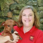 Dawn Sims, Certified Professional Dog Trainer in Rudy, Arkansas holding her paraplegic dachshund